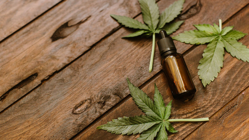 cbd oil bottle on a wooden table with hem leaf