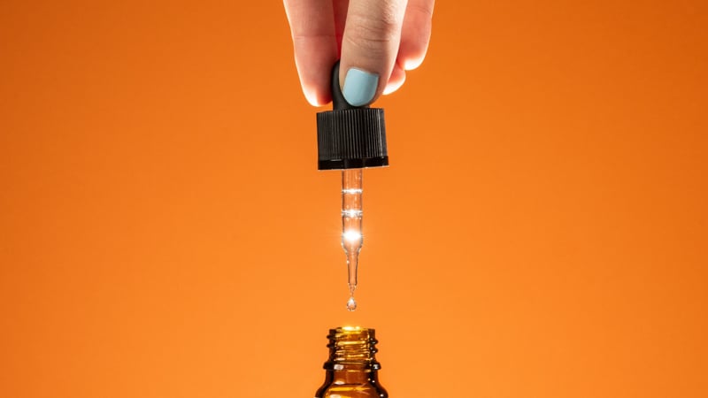 dropper from cbd oil with orange background