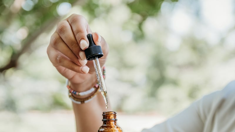 A person is holding CBD Oil Dropper with nature in the background